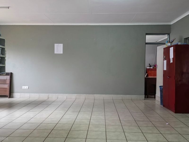 A spacious, neutrally painted living area featuring tiled flooring and a secure entrance, offering a blank canvas for interior design.