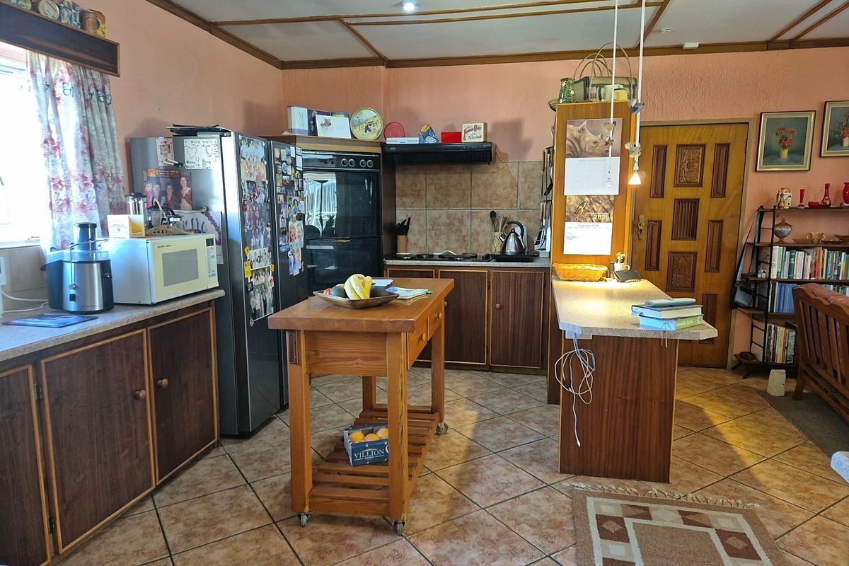 A dated kitchen featuring wood-look cabinetry, tiled flooring, a built-in oven, and a functional peninsula counter, offering potential for a modern renovation.