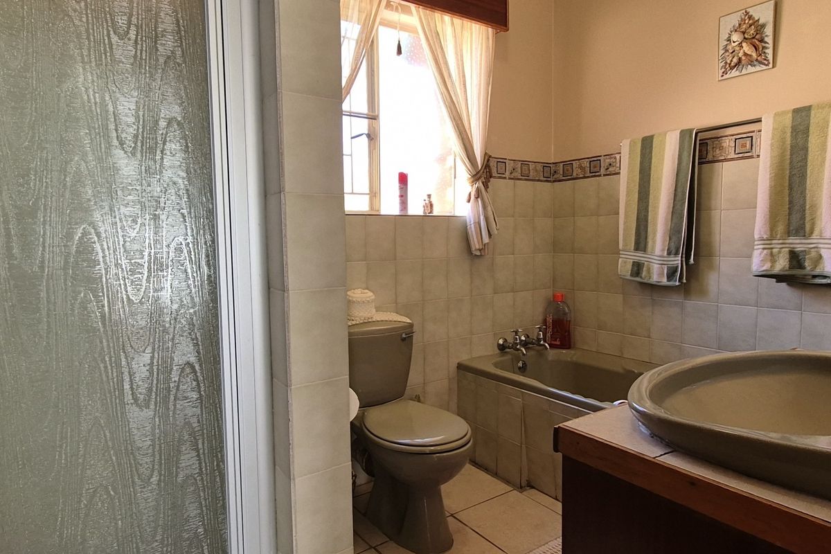 A functional bathroom featuring a built-in bathtub, toilet, vanity basin, and a separate shower enclosure with tiled finishes throughout.