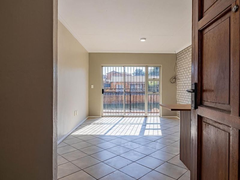 An open-plan living area featuring tiled floors, a brick accent wall, a breakfast bar, and a sliding door leading to an outdoor space.
