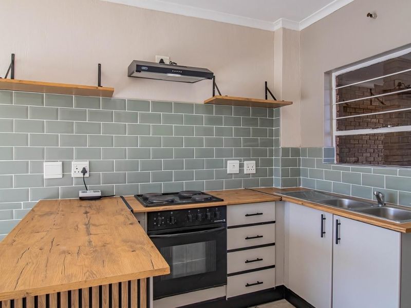Modern kitchen featuring subway tile backsplash, wooden countertops, built-in oven with hob, extractor fan, and stainless steel double sink with ample storage cabinetry.