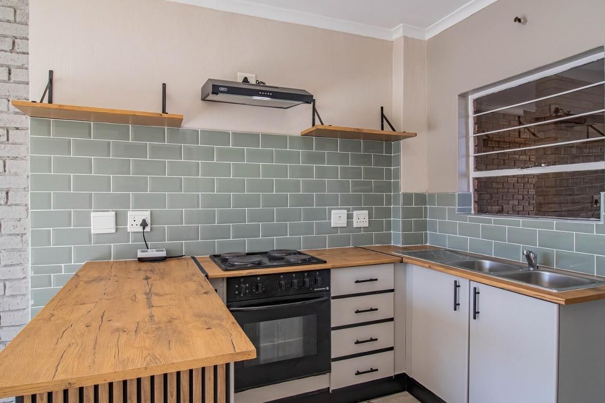 Modern kitchen featuring subway tile backsplash, wooden countertops, built-in oven with hob, extractor fan, and stainless steel double sink with ample storage cabinetry.