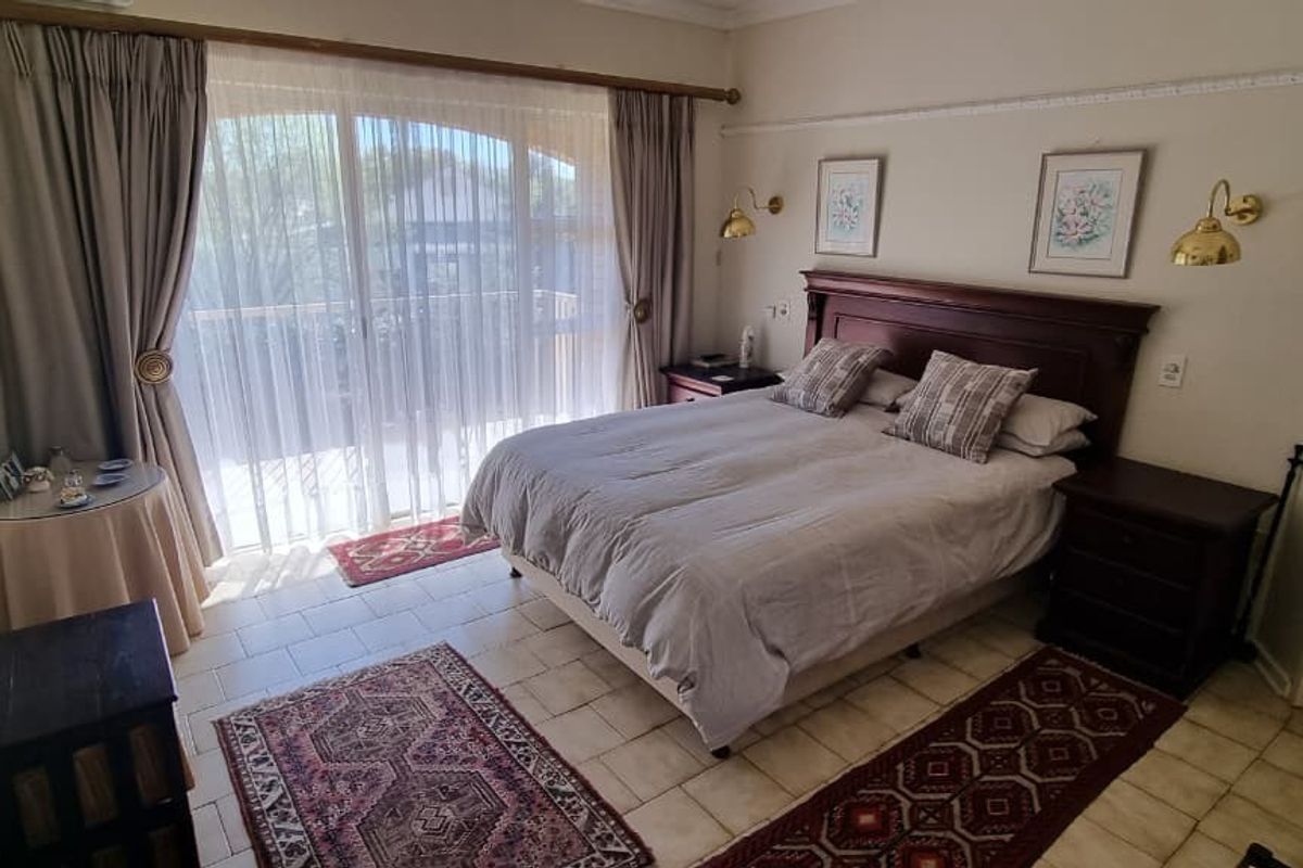A bedroom featuring tiled flooring, wall-mounted lighting, and a sliding glass door providing access to an outdoor area.
