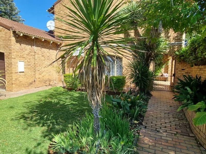 Front exterior view of the property featuring a brick facade, paved walkway, and well-maintained garden area with established landscaping.