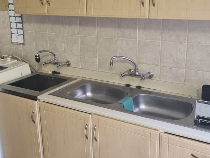 Functional laundry area featuring double and single stainless steel sinks, wall-mounted taps, laminate cabinetry, and tiled splashback.