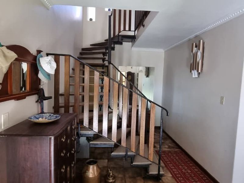 Welcoming entrance hall featuring a distinctive staircase with wooden treads and wrought iron balustrade, complemented by tiled flooring and crown molding.
