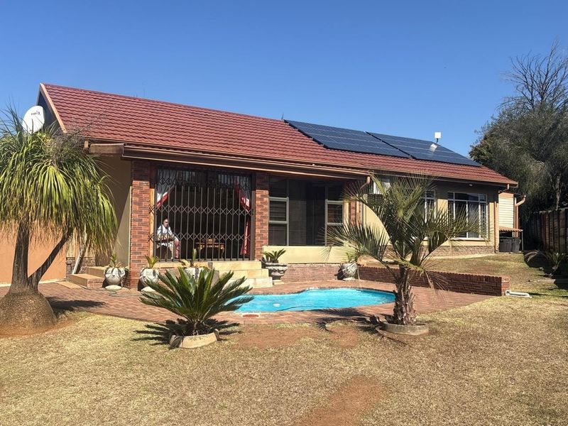 Rear view of the house featuring a swimming pool, brick paved patio area, and roof-mounted solar panels.