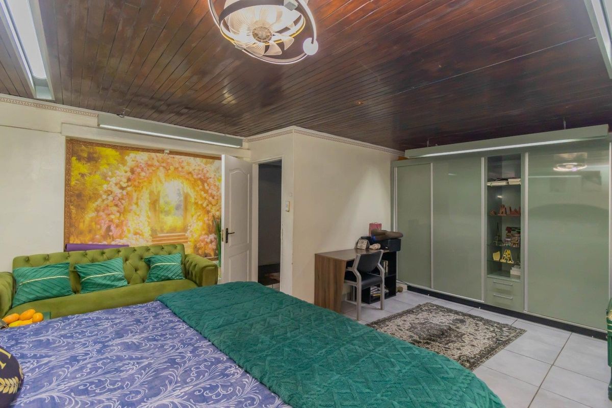 Spacious bedroom featuring a dark timber ceiling, tiled flooring, and a large built-in wardrobe with integrated shelving.