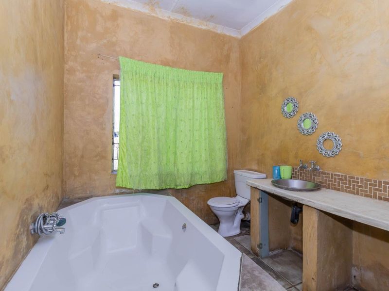 Bathroom featuring a built-in bathtub, toilet, and a custom concrete vanity with a vessel sink, requiring cosmetic updates to the wall finishes.