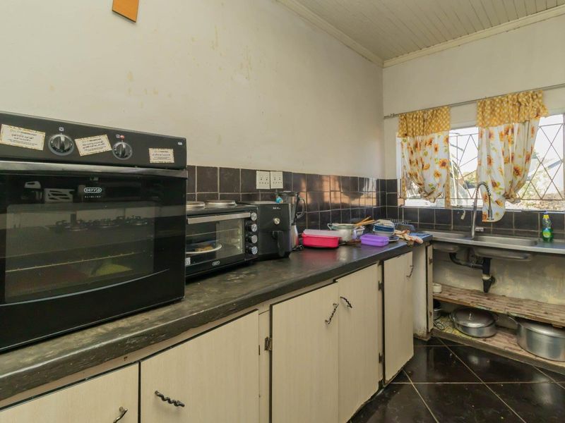 A functional kitchen featuring built-in oven, tiled backsplash, and laminate cabinetry, currently showing signs of wear and requiring cosmetic updates.