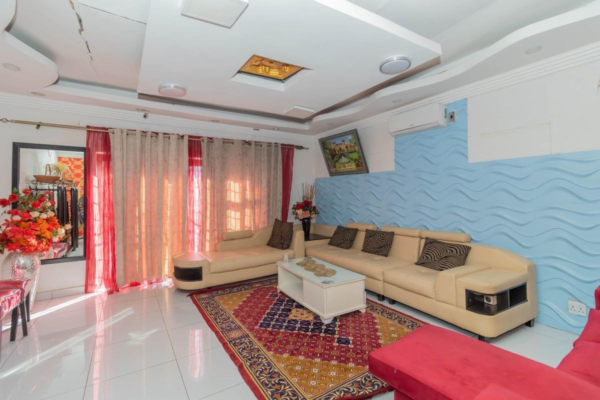 Living room featuring a recessed ceiling, tiled flooring, split system air conditioning, and a textured blue feature wall.