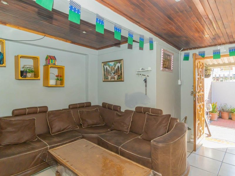 A living room featuring a timber-paneled ceiling, tiled flooring, and direct access to an outdoor patio area.