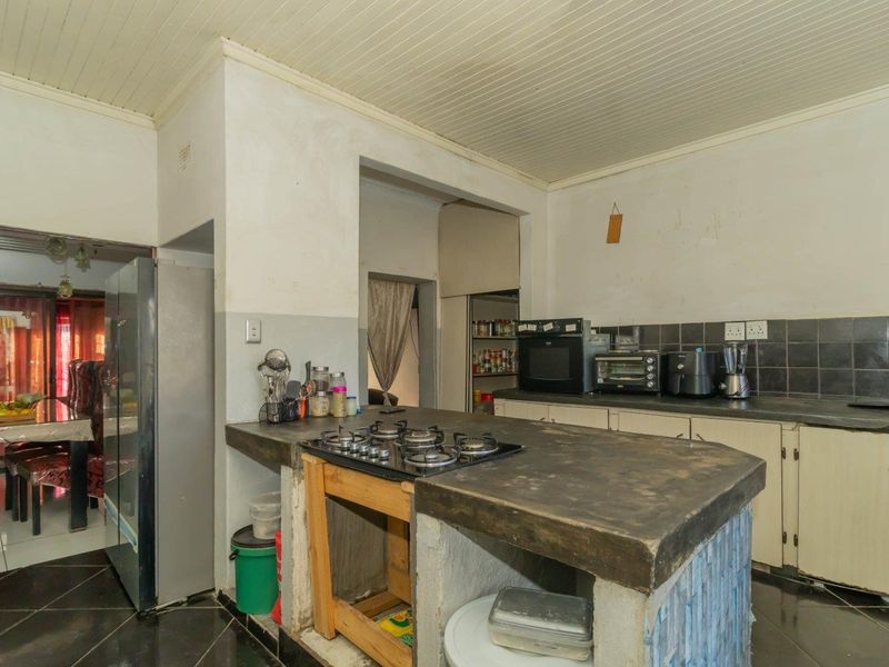 Kitchen featuring a concrete island with a built-in gas hob, tiled backsplash, and ample cabinetry, offering potential for a modern renovation.