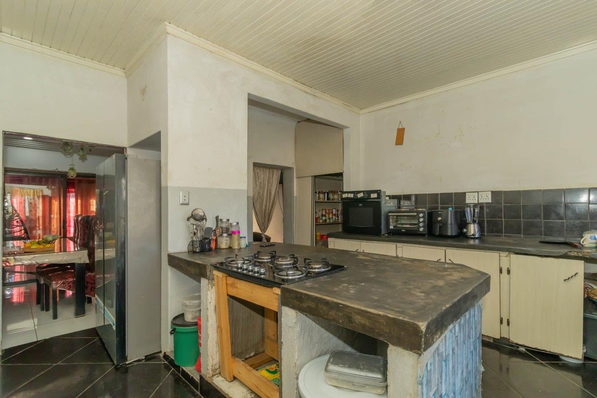 Kitchen featuring a concrete island with a built-in gas hob, tiled backsplash, and ample cabinetry, offering potential for a modern renovation.