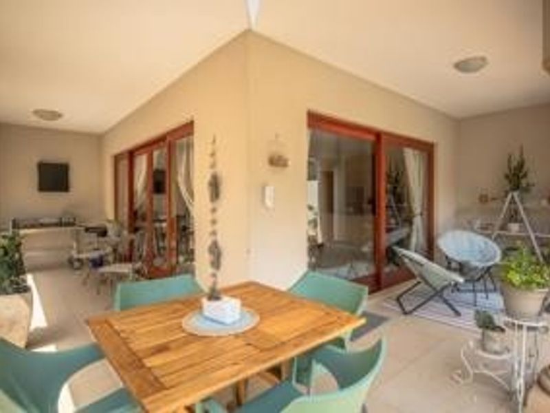 A spacious covered patio featuring tiled flooring, recessed lighting, and large sliding glass doors providing seamless access to the interior living areas.