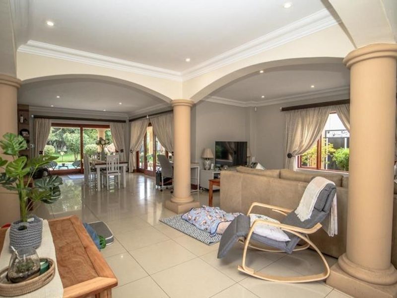 Spacious open-plan living and dining area featuring elegant archways, decorative columns, tiled flooring, and large sliding glass doors providing ample natural light.