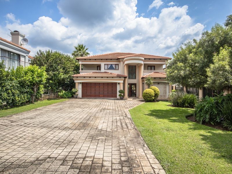Front elevation of a two-story residential property featuring a paved driveway, double garage, and established garden.