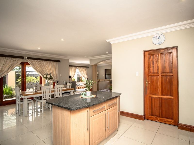 Spacious open-plan kitchen and dining area featuring a central island with granite countertops, tiled flooring, and seamless flow to the outdoor patio.