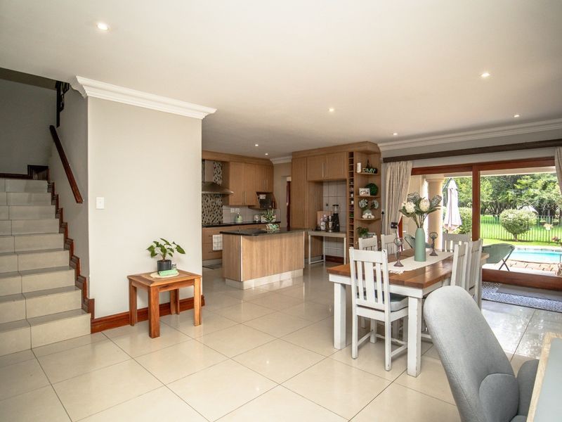 Spacious open-plan living and dining area featuring tiled floors, a modern kitchen with granite countertops, and direct access to the outdoor pool area.