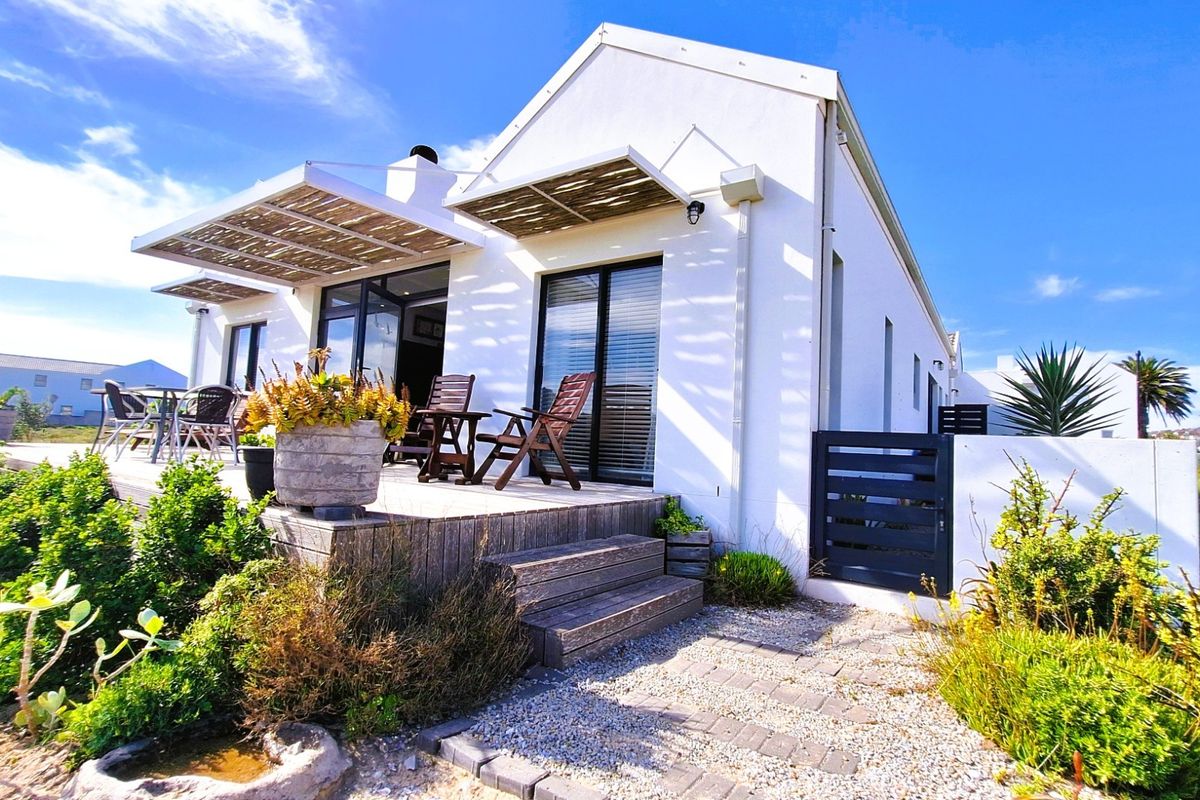 Rear elevation of a modern house featuring a timber deck, pergola, and sliding glass doors leading to a landscaped garden area.