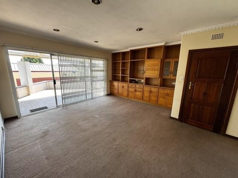 Spacious living room featuring built-in wooden cabinetry, recessed lighting, and large sliding glass doors providing access to an outdoor patio area.