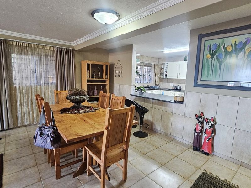 Open plan dining area featuring tiled flooring and a breakfast bar connecting to the kitchen, finished with decorative cove molding.