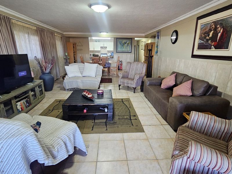 Spacious open-plan living and dining area featuring tiled flooring, wall tiling, and neutral finishes, providing a versatile layout for family living.