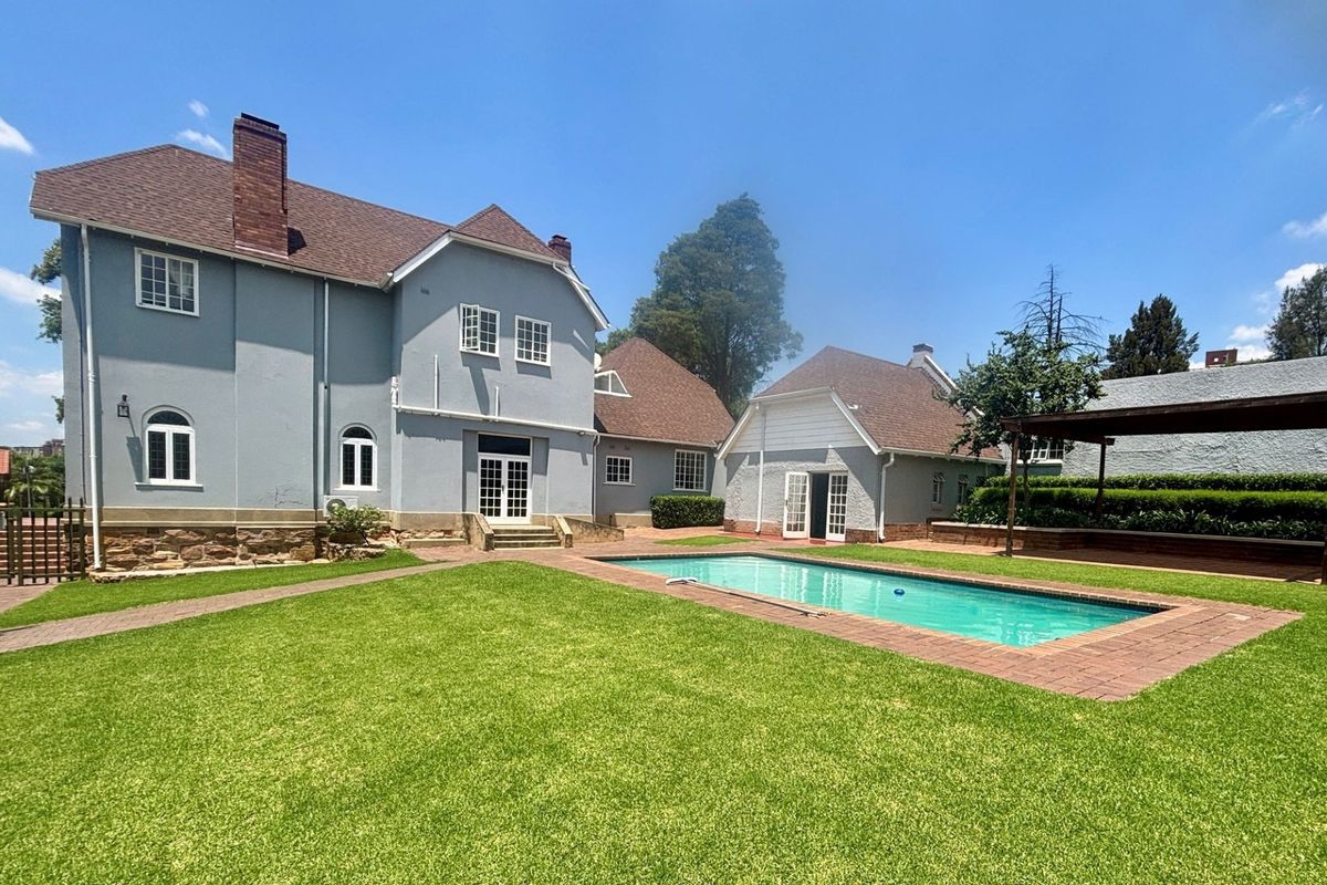 Spacious rear garden featuring a well-maintained swimming pool, brick paving, and a pergola, set against the backdrop of a charming multi-story townhouse.
