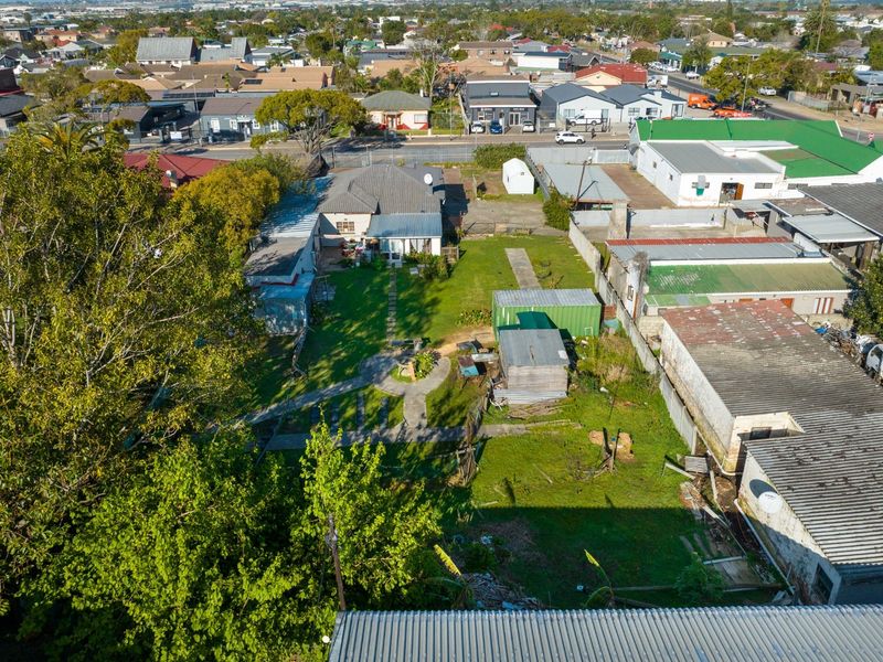 Aerial view of the commercial property site, showcasing the main building, surrounding outbuildings, garden area, and access pathways within the urban context.