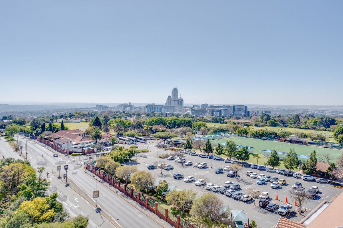 An elevated aerial view showcasing the surrounding urban landscape, nearby sports facilities, and parking infrastructure.
