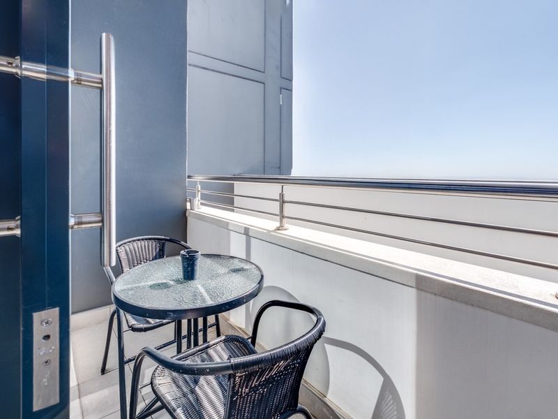 A modern apartment balcony featuring a stainless steel balustrade and tiled flooring, offering an open outdoor space.