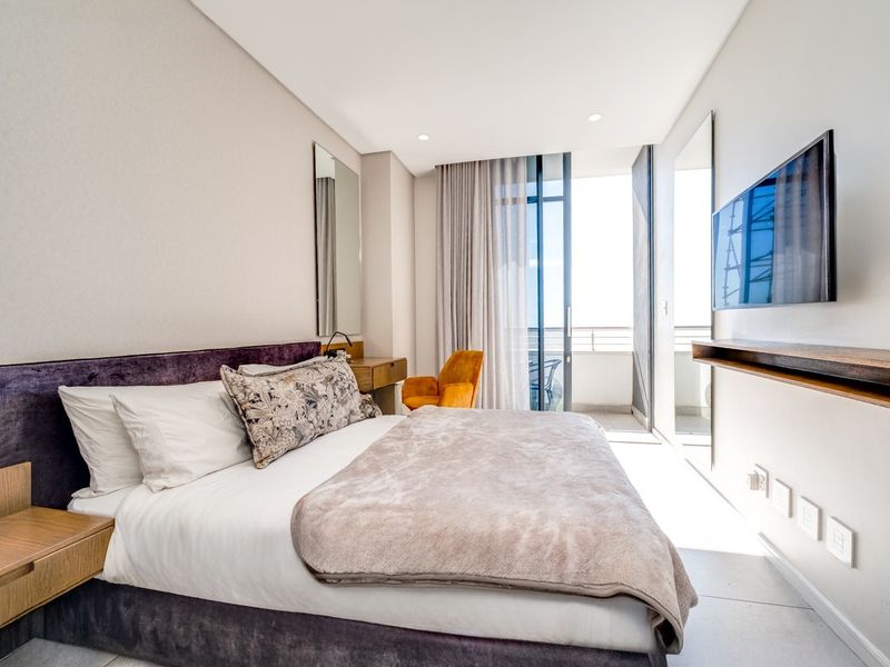 Modern bedroom featuring tiled flooring, recessed lighting, a built-in vanity, and a sliding glass door providing access to a private balcony.