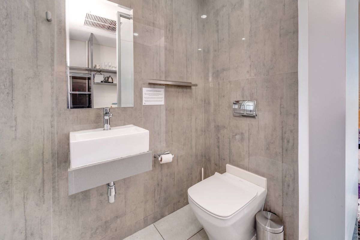 Modern bathroom featuring a wall-mounted basin, wall-hung toilet, and contemporary grey tiled finishes throughout.