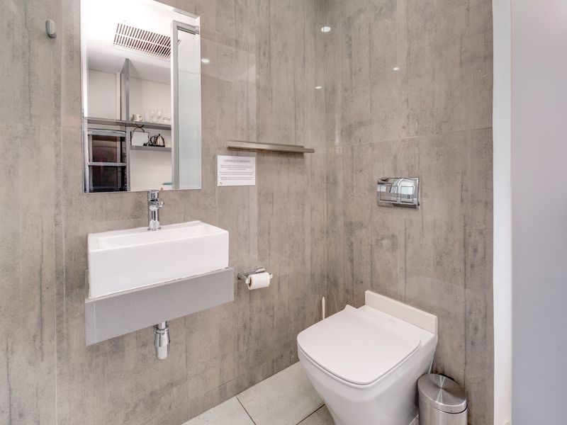 Modern bathroom featuring a wall-mounted basin, wall-hung toilet, and contemporary grey tiled finishes throughout.