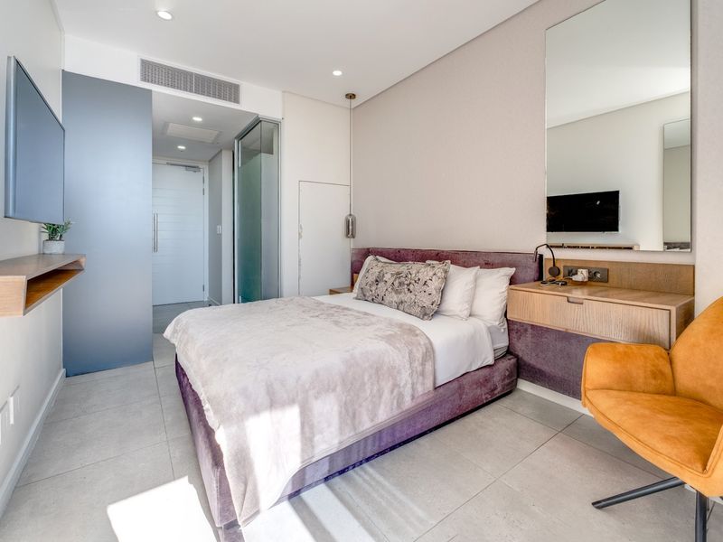 Modern bedroom featuring tiled flooring, built-in vanity with mirror, recessed lighting, and integrated ducted air conditioning.