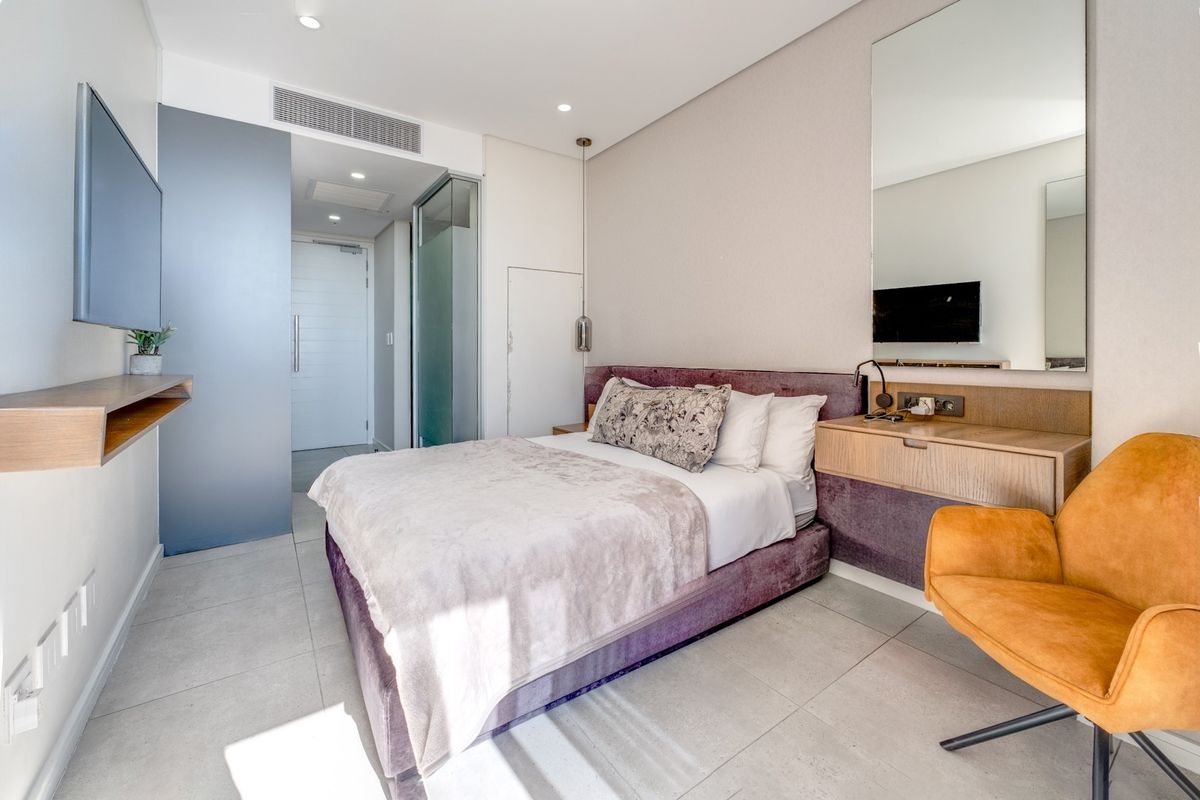 Modern bedroom featuring tiled flooring, built-in vanity with mirror, recessed lighting, and integrated ducted air conditioning.