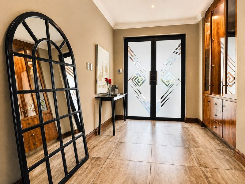 Elegant entrance hall featuring tiled flooring, custom built-in wooden cabinetry, and striking double glass doors with decorative frosted detailing.