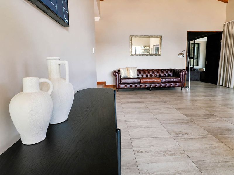 Spacious living area featuring large format floor tiles, high vaulted ceilings, and neutral wall finishes, creating an open and airy atmosphere.