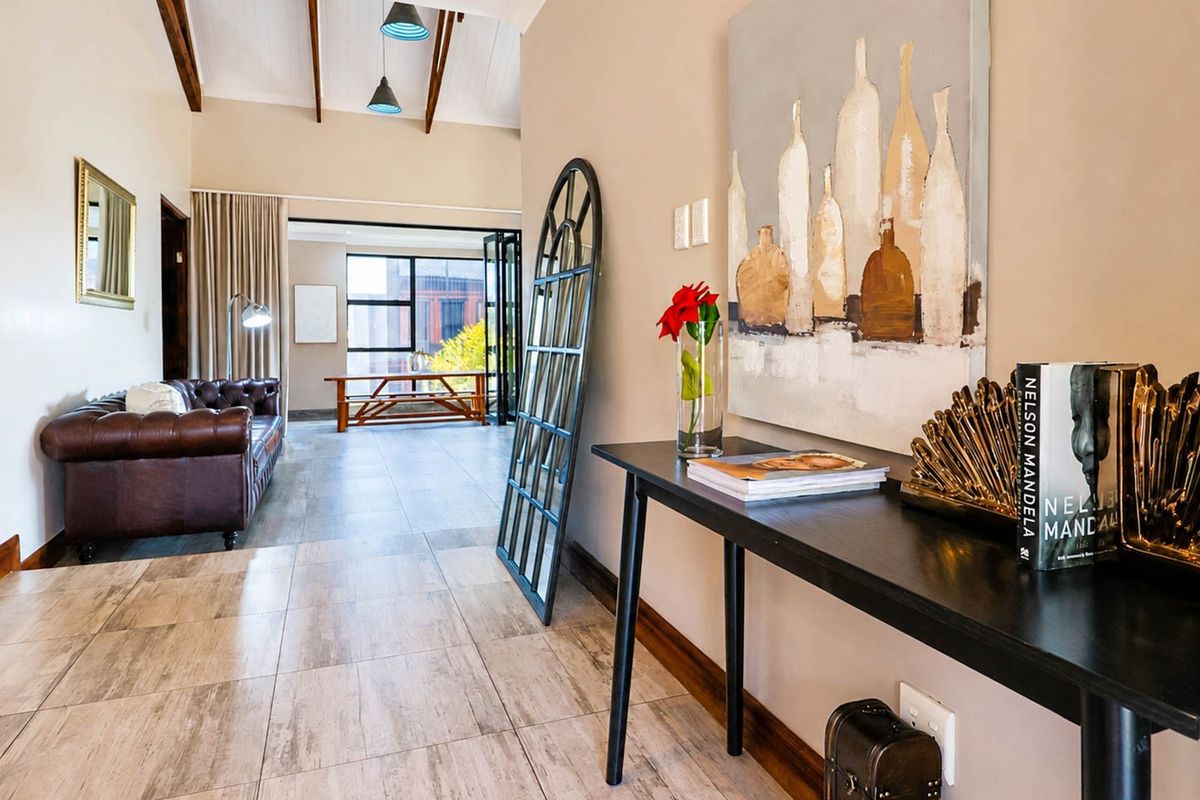 Spacious living area featuring vaulted ceilings with exposed timber beams, tiled flooring, and bi-fold doors leading to an outdoor space.