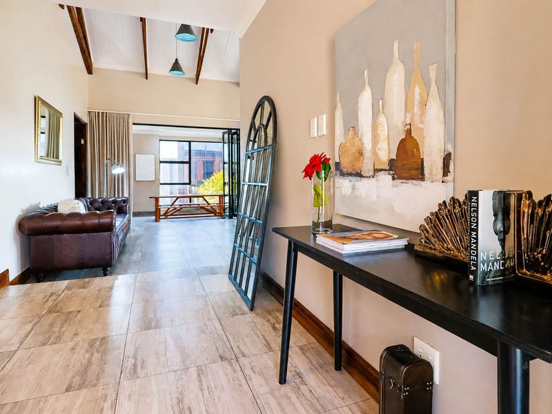 Spacious living area featuring vaulted ceilings with exposed timber beams, tiled flooring, and bi-fold doors leading to an outdoor space.