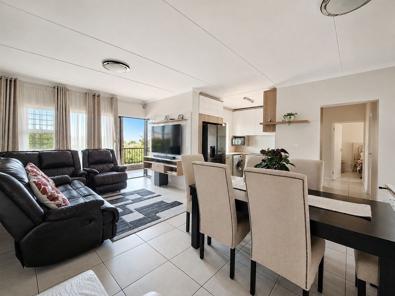 Spacious open-plan living and dining area featuring tiled floors, modern kitchen cabinetry, and direct access to a private balcony.