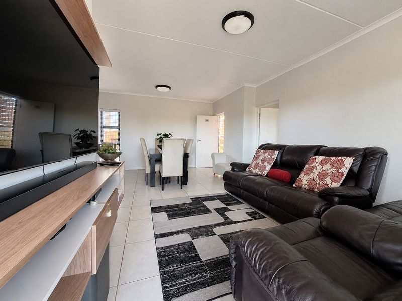 An open-plan living and dining area featuring neutral tiled flooring, clean white walls, and functional ceiling lighting, creating a bright and cohesive living space.