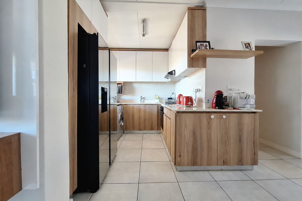 Modern kitchen featuring wood-grain and white cabinetry, tiled flooring, integrated appliance spaces, and a functional layout with ample counter space.