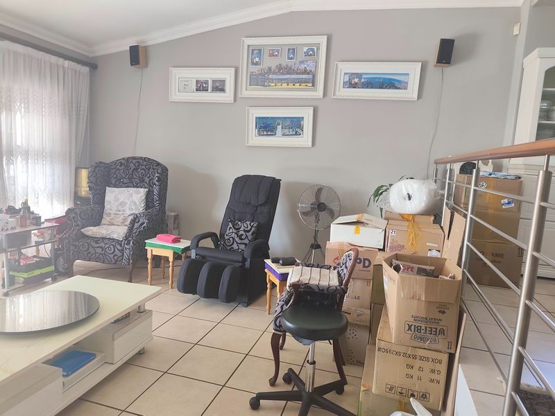 A living room area featuring tiled flooring, a stainless steel balustrade, and wall-mounted speakers, providing a functional space for relaxation.