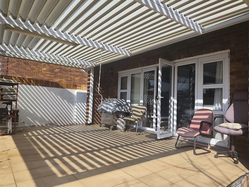 Covered patio area featuring a louvre roof system, tiled flooring, and direct access to the interior through white-framed french doors.