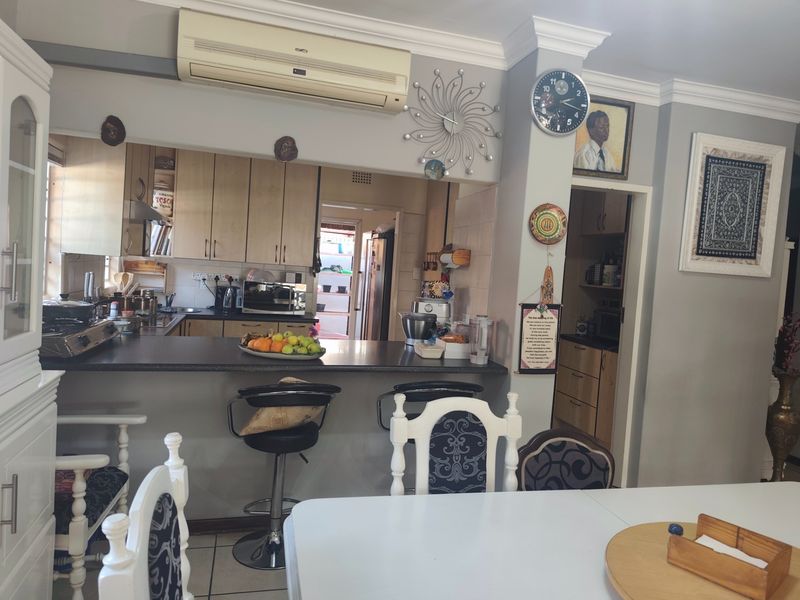 Open-plan kitchen and dining area featuring a breakfast bar, ample cabinetry, and wall-mounted air conditioning, providing a functional layout for daily living.
