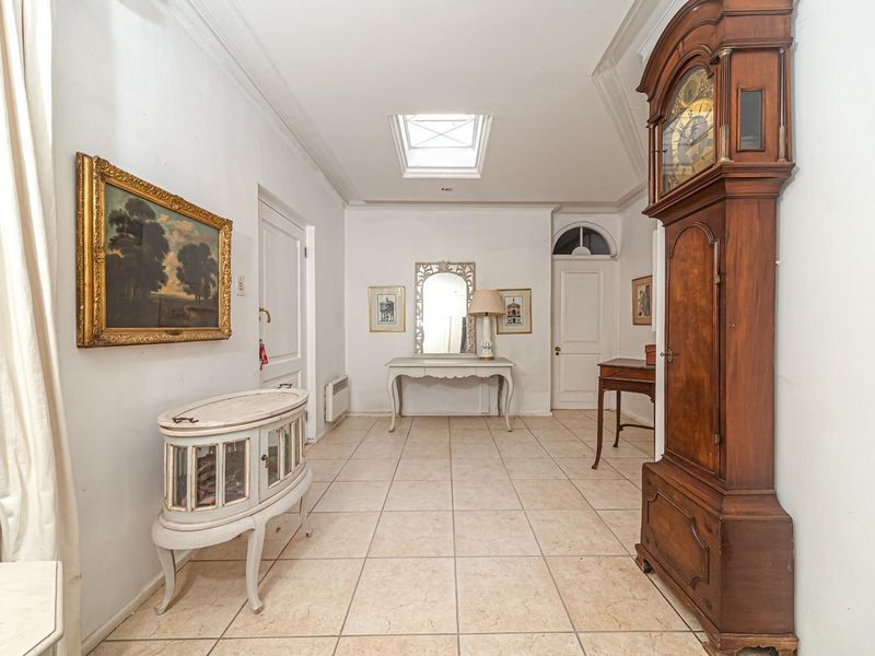 A spacious, well-lit hallway featuring neutral tiled flooring and a central skylight, providing a bright and welcoming entrance area.