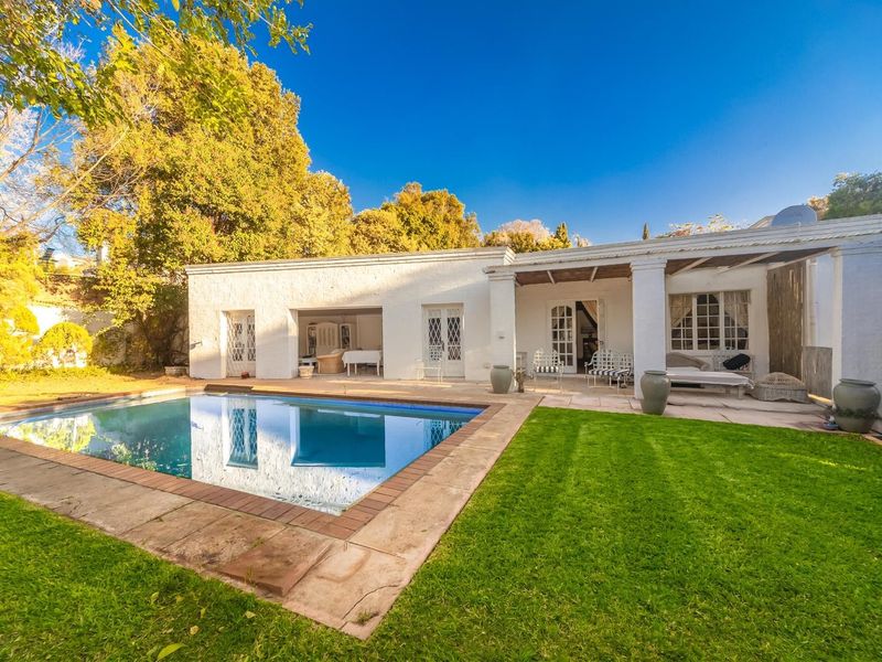 Outdoor pool area featuring a swimming pool with brick coping, a covered patio with masonry columns, and a well-maintained lawn.