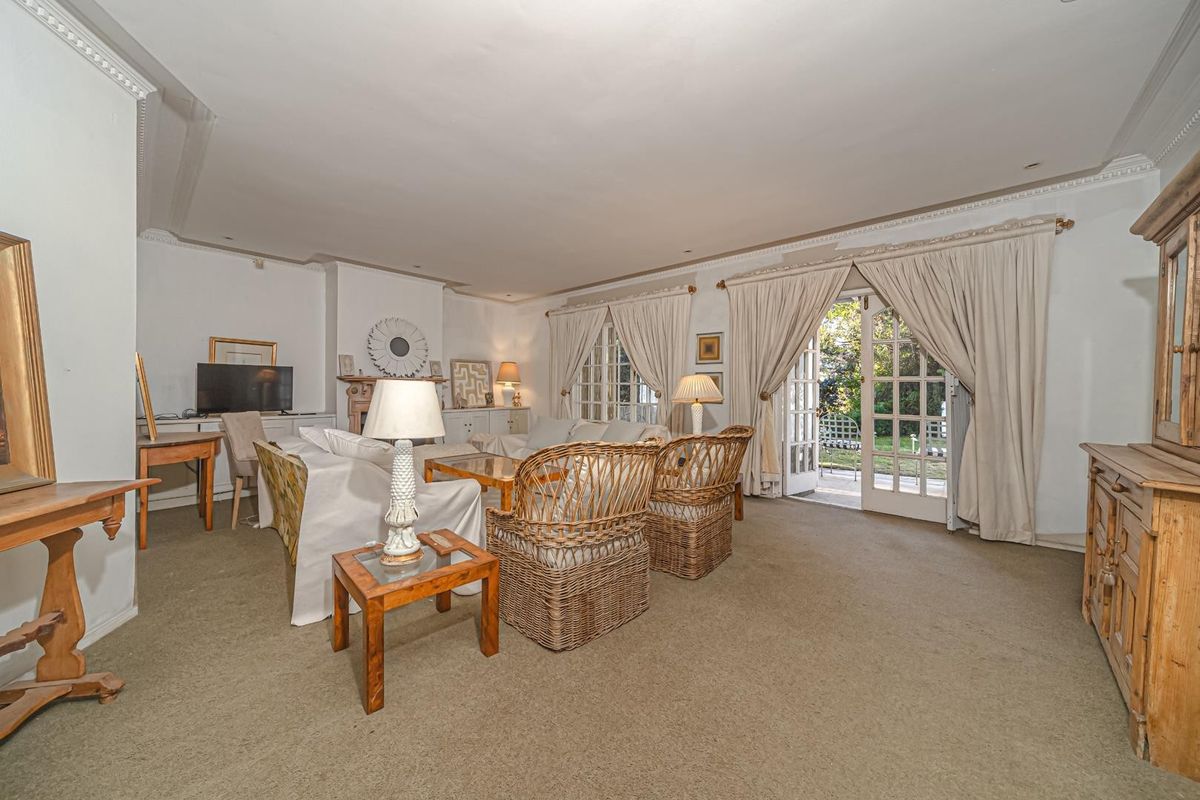 Spacious living room featuring a fireplace, crown molding, and direct access to the garden through classic french doors.