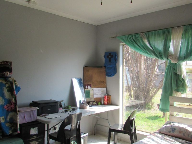 A bedroom featuring tiled flooring, a ceiling fan, and a sliding glass door providing natural light and garden access.